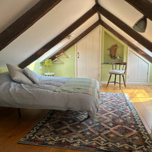 Load image into Gallery viewer, Mezzanine bedroom with a bed, rug, and view into towards the shower room.
