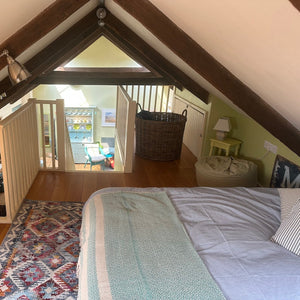 mezzanine bedroom with a bed, rug, and wooden floor.
