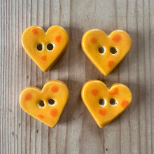 Load image into Gallery viewer, Four yellow heart-shaped buttons with orange spots on a wooden surface
