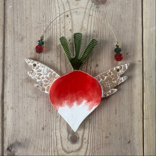 Decorative radish ornament with wings on a wooden surface