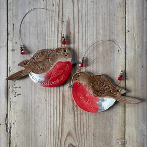 Two ceramic robin bird ornaments on a wooden background