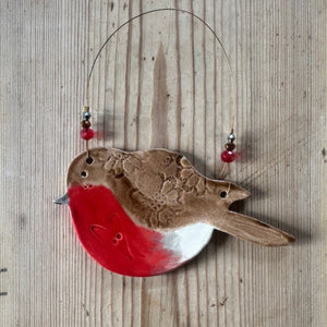 Decorative bird ornament with red breast on a wooden background