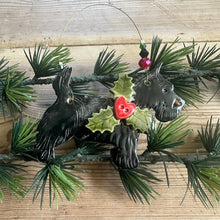 Load image into Gallery viewer, Decorative wall hanging with black dog figures and greenery on a wooden surface
