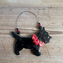 Load image into Gallery viewer, Black dog-shaped ornament with red hearts on a wooden surface
