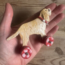Load image into Gallery viewer, Hand holding a dog shaped object with red wheels on a wooden surface
