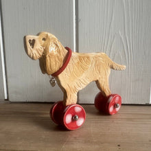 Load image into Gallery viewer, ceramic dog ornament with red wheels on a wooden surface
