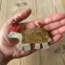 Load image into Gallery viewer, Hand holding a tortoise shaped ornament with a wooden background
