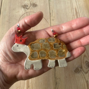 Hand holding a tortoise shaped ornament with a wooden background